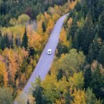 Rv on an open road surrounded by yellow trees
